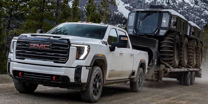 2026 GMC Sierra 2500 HD Pro towing heavy equipment on a trailer