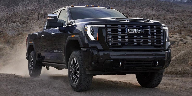2026 GMC Sierra 2500 HD Pro driving on a rugged dirt road